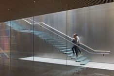 a woman is walking down the stairs in a building with glass walls and railings