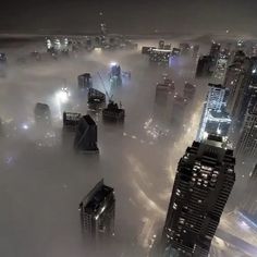 the city is surrounded by fog and skyscrapers