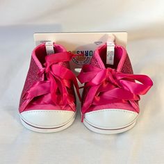 a pair of pink shoes with bows on the front and bottom, sitting in a box