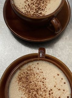 two brown bowls filled with liquid on top of a table