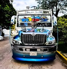 a blue and white truck parked on the side of a road with trees in the background