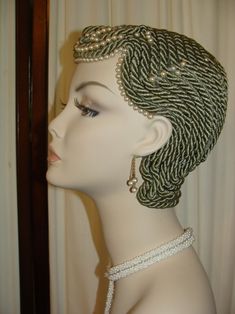 a white mannequin head with braids and pearls on it's head