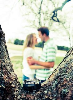 a man and woman standing next to each other in front of a tree with a camera on it