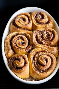 cinnamon rolls in a white bowl on top of a stove