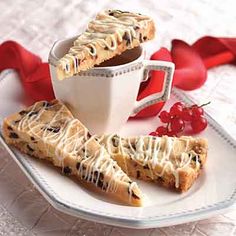 two pieces of chocolate chip cookies on a plate with a cup of coffee and cherries