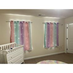 a baby's room with pink, blue and green curtains