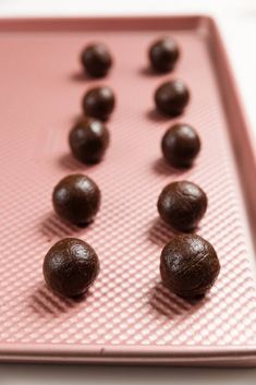 chocolate candies are arranged on a pink tray