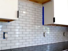 a kitchen with white tile and blue trim on the backsplashes, cabinets and counters