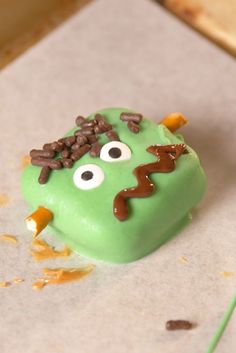 a green cake with chocolate sprinkles and eyes on it's face