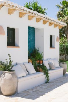 a white couch sitting in front of a building with potted plants next to it