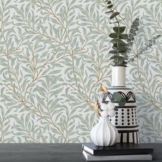 a vase filled with flowers sitting on top of a table next to a wall paper