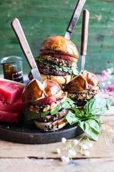 several hamburgers are stacked on top of each other with knives sticking out of them