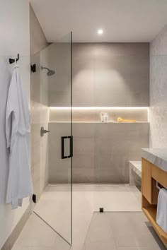 a bathroom with a glass shower door and white towels hanging on the wall next to it