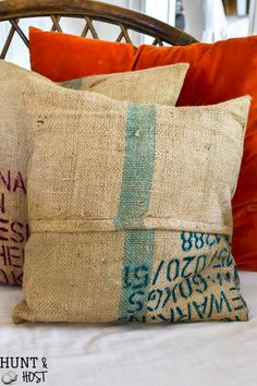 two pillows sitting on top of a bed next to an orange pillow cover with writing on it