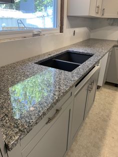 an empty kitchen with granite counter tops and white cabinets in the back drop off area