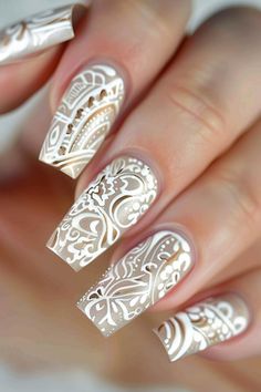 Close-up of a hand displaying nails with intricate white lace-patterned nail art on a shimmering base. Nail Stamping Ideas, White Nail