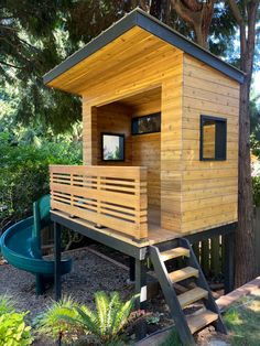 a small wooden structure with stairs leading up to it and a slide in the background