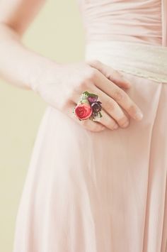 a woman in a pink dress holding onto a rose ring