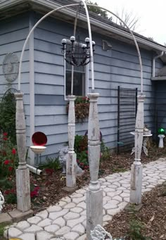 an outdoor garden area with white pillars and lights on the side of a blue house