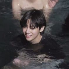 a man in the water with his shirt off and some other people behind him smiling