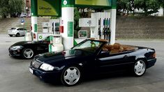 two cars are parked at a gas station