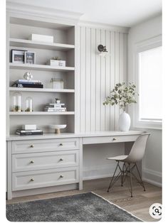 a white desk sitting next to a window in a room with bookshelves and shelves