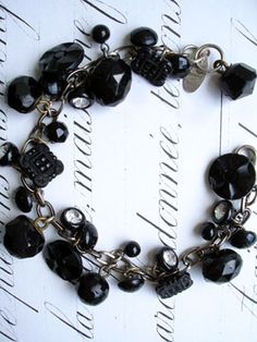 a bracelet with black beads and charms on it's sides, sitting on top of a white background