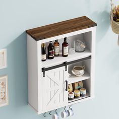 a white cabinet with bottles and spices on it next to a wall mounted potted plant