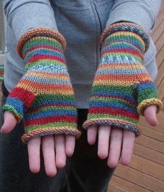 a person wearing colorful knitted gloves with their hands in the shape of mitts