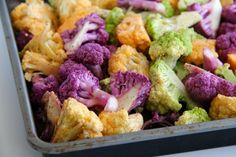 a pan filled with cauliflower and broccoli on top of a table