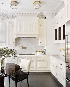 an elegant kitchen with white cabinets and black counter tops, along with gold trimmings