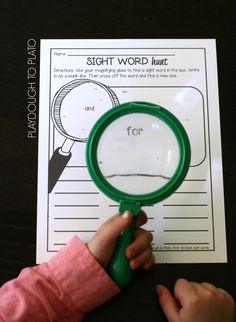 a hand holding a magnifying glass over a piece of paper that says sight word hunt