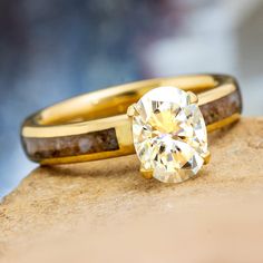 two yellow gold wedding rings with a diamond in the center on top of a rock