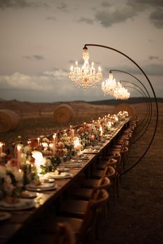 a long table is set up with candles and plates for an outdoor dinner party in the desert