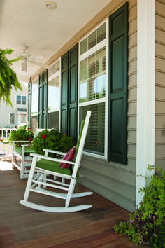 a white rocking chair sitting on top of a wooden porch next to a green planter