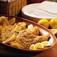 fried fish and lemons in a dish on a table