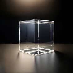 an empty glass box sitting on top of a table next to a light bulb in the dark