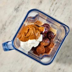 a blender filled with ice cream, fruit and other toppings on a marble surface