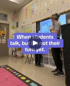 two students are standing in front of a projector screen and talking to each other