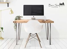 a desktop computer sitting on top of a wooden desk next to a white chair and potted plant