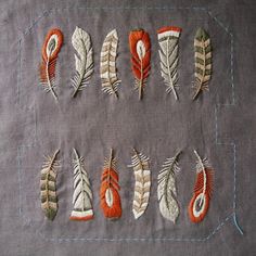 several embroidered feathers are arranged on a piece of fabric with stitching in the middle