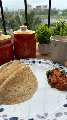 a plate with some food on top of it next to two cups and saucers