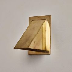 a gold square shaped object on a white wall