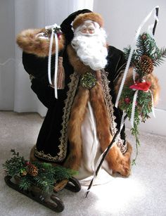 a santa claus doll sitting on the floor next to some pine cones and other decorations