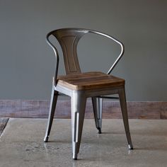 a chair sitting on top of a cement floor next to a wooden table and wall