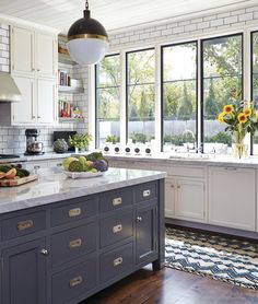 a large kitchen with white cabinets and wood flooring, along with an island in the middle