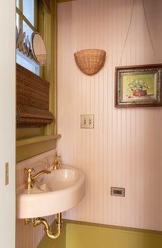 a sink and mirror in a small room with pink wall paper on the walls behind it