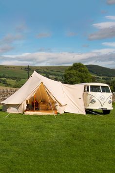 an old vw camper van is parked in the grass near a stone wall