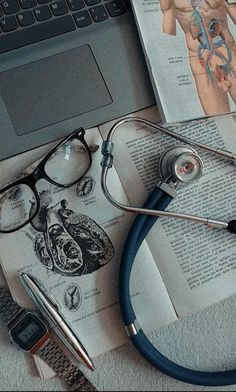 a stethoscope, glasses and book on top of a table next to a laptop