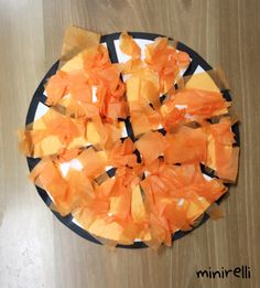 orange pieces of tissue paper on a black and white plate sitting on a wooden table